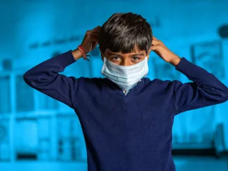 Young boy in blue wearing a facemask