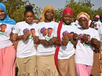 5 young girls stand with arms locked, looking at the camera in Ouahigouya, in the North of Burkina Faso.