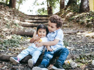 Older child hugging toddler on a nature path
