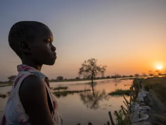 13 year old Ayak Anhiany Lual walks past flooded water outside the village of Panyagor in Twic East, Jonglei State in South Sudan.