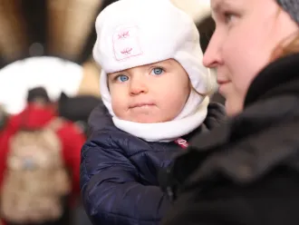 On 27 February 2022, as military operations continue in Ukraine, a woman carrying a small child waits to board an evacuation train at the railway station in Lviv, in Ukraine's westernmost corner, near the Polish border.