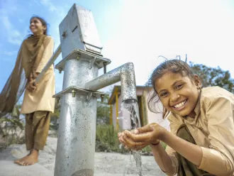 A young girl pumps safe water for drinking in Rajasthan, India. 