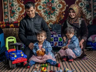  2-year-old twin sisters Fotima (left) and Zuhro pose for a portrait with their parents Namazqul Eshquvatov (left), 27, and Rahima Kushakova, 23, at their home in Burmai Poyon village.