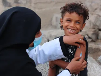 Au Yémen, un enfant sourit à l’objectif en se faisant vacciner.
