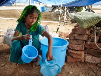 On 14 September 2022, sitting on floor of her shared tent, Geetu, 8 years old, shows off a hygiene kit her family received from UNICEF at Mohammad Medical Emergency Camp in Umerkot District, Sindh Province, Pakistan.