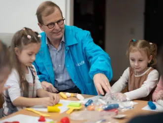 David Morley interacting with children sitting at child's table. 