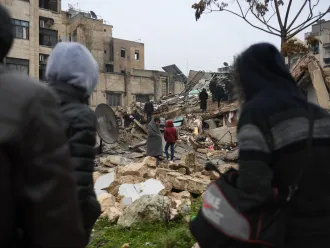 On 6 February 2023, people gather around collapsed buildings as rescue teams look for survivors following an earthquake in the government-held Syrian city of Aleppo. 