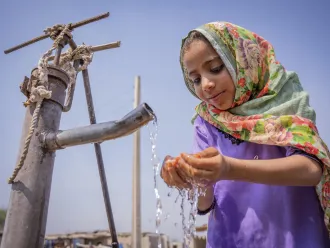 Nafisa (6) drinking water from a community handpump.