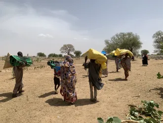 On 28 April 2023, as they cross into Koufroun, a Chadian village near the Sudanese border, refugees from Sudan carry their personal belongings.
