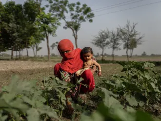 A mother works in the fields with her six-month baby in South Punjab Province.