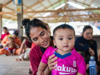 Mother holding her baby at a community vaccination session in Preah Vihear, Cambodia.