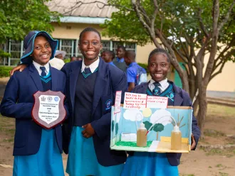 Three girls pose for a photo after winning an award at a STEM fair.