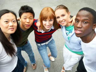 Five young people of diverse ethnic backgrounds look upwards smiling