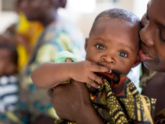 Mother in Tanzania holding her baby close, cheek to cheek.
