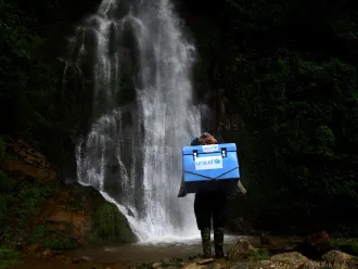 A vaccinator climbs a rocky path.