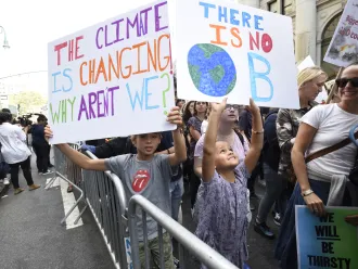 Young people at a climate protest holding placards on climate change.