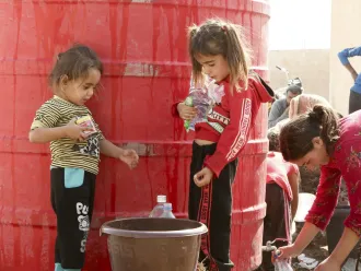 En Syrie, deux jeunes filles remplissent un seau d'eau