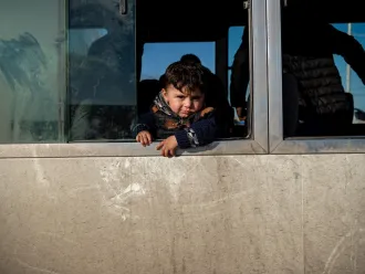 A child looks out a bus window at a temporary camp for Syrian refugees in Iraq.