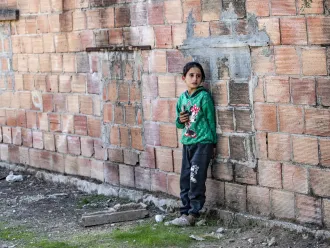 A child stands outside the ruins of a building in rural Syria.