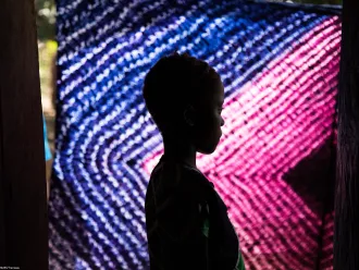 A young girl poses in front of a vibrant, colorful curtain