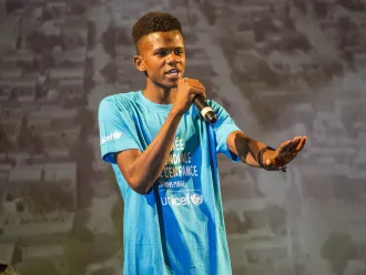 Teen boy holding microphone where World Children's Day cyan blue shirt