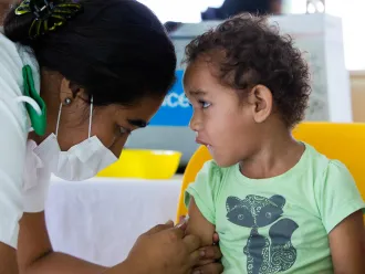 A little boy watches a nurse as he receives a vaccine shot.