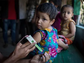 Une fillette passe un test de dépistage de la malnutrition dans une clinique soutenue par l’UNICEF dans un camp pour personnes réfugiées à Cox’s Bazar, au Bangladesh.