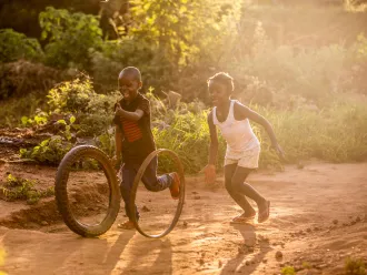 Maria and her friend play as the sun sets in Zambia. Her father Clement, receives UNICEF-supported cash transfers, which help him give her nourishment and protection