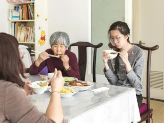 A girl in Beijing eats lunch with her family.