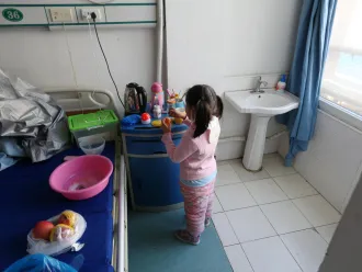 Yuanyuan washes her hands in the hospital ward where she is currently under isolation.