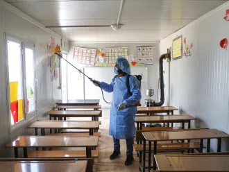  A Syrian volunteer disinfects a classroom in rural Idlib.