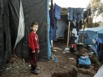 A boy stands in a makeshift camp for refugees.