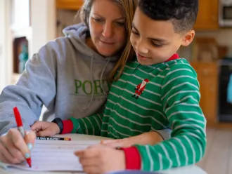 A child and mother study together at home.