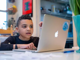 Boy doing homework on laptop at kitchen table