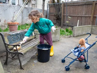 A little girl cleans her play area with soap and water.