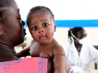 A mother holds her baby at a mobile clinic.