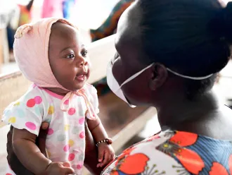 Amusée par le visage masqué de sa mère, Christelle, 3 mois, attend d’être vaccinée dans un centre de santé près d’Abidjan, en Côte d’Ivoire. 