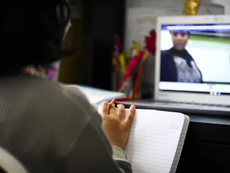 A student watches an lecture through their computer.