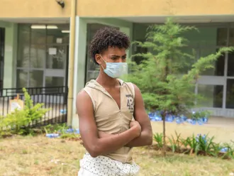 A young man stands outside a shelter for trafficked youth.