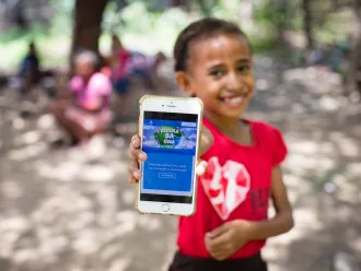 Child in Timor-Leste holding up cell phone with the Learning Passport on the display