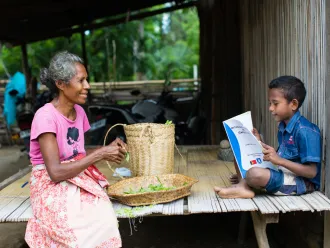 A boy reads to his grandmother in Dalli, Timor Leste.