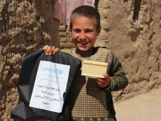 A boy shows off a bag of WASH supplies and a bar of soap.