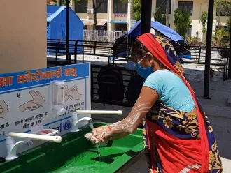 A woman washes her hands at a portable washing station.