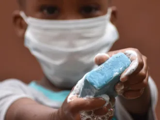 A little boy holds up a bar of soap.
