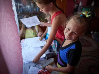 On 6 August 2020, sisters receive educational materials, including colouring books and exercise books, during a visit of a social worker and psychologist to their home in in Bilokurakyne, Eastern Ukraine.