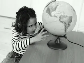 Young girl looking at a globe on a desk