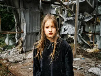 Arina, 10, stands on the spot where a shop used to be – right next to the children's playground in the village of Mala Rohan, in the Kharkiv region. Now it is a pile of rubble.