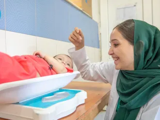 A doctor is weighing a baby in nutrition section in a Community Health Center in Herat, Afghanistan.