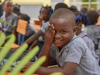 A young boy smiles during the inauguration ceremony of his school in Maingrette.