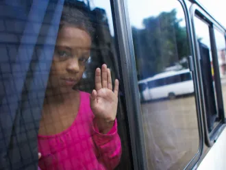 Edguimar (10), looks out of the window of the bus that will transport her to Tegucigalpa to follow the migration route to the United States, after leaving the Temporary Rest Center "Alivio del Sufrimiento" located in El Paraíso, on November 4, 2023 in Honduras.